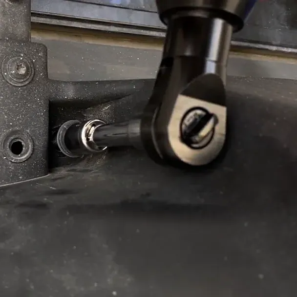 The SuperRatchet's head, with its direction knob, turning a socket on an extension into a bracket bolt