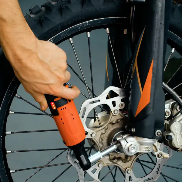A hand runs the SuperRatchet on an extension into a dirt bike's front axle nut