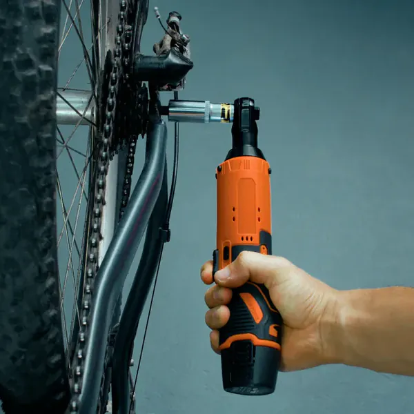 A hand holds the SuperRatchet upright with its socket on a mountain bike's rear axle nut